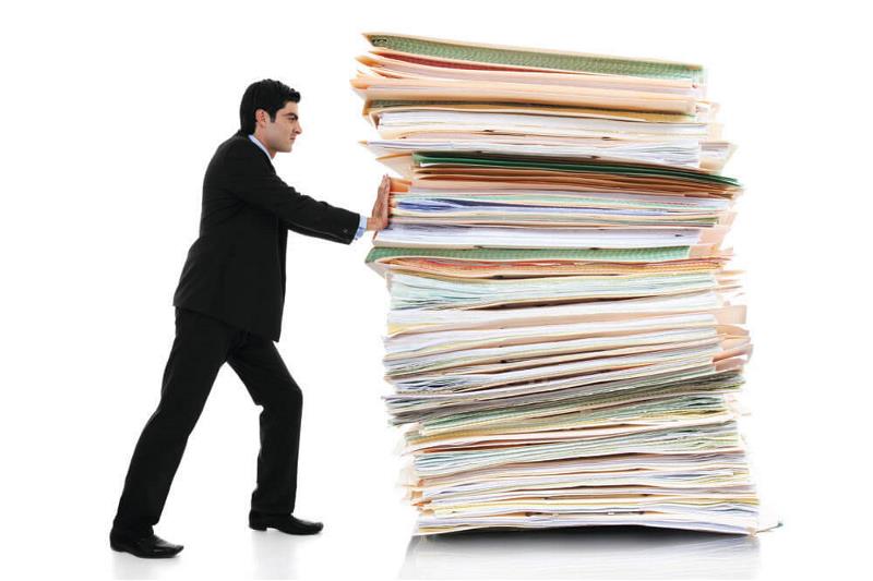 A man pushing a large pile of files