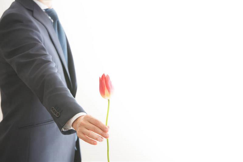 A corporately dressed man holding a flower