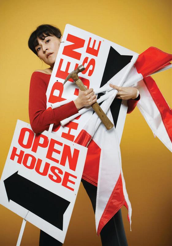 A lady with open house sign and an hammer